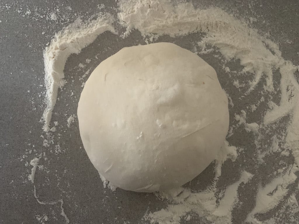 A gently shaped dough ball next to some flour.